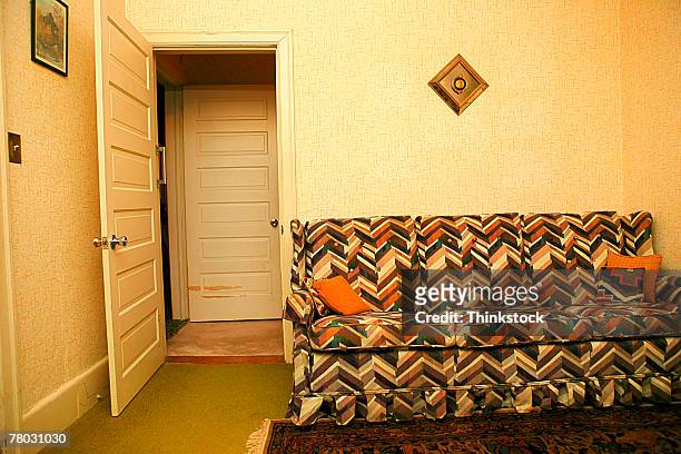 a retro couch against a wall in a room with an open door. - kitsch photos et images de collection
