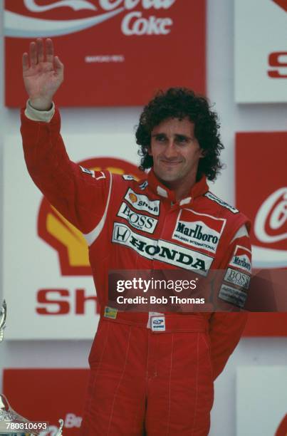 French racing driver Alain Prost waves to the crowd from the podium after driving the Honda Marlboro McLaren McLaren MP4/4 Honda V6 turbo to finish...