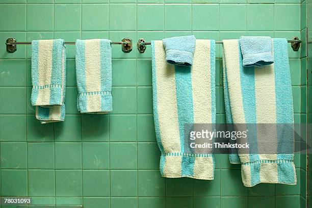 close-up in a 1950s style bathroom of blue and white striped towels hanging against a green tiled wall. - washcloth stockfoto's en -beelden