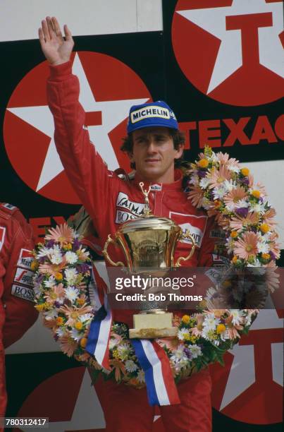 French racing driver Alain Prost waves to crowds of supporters from the podium after driving the Marlboro McLaren International McLaren MP4/2B...
