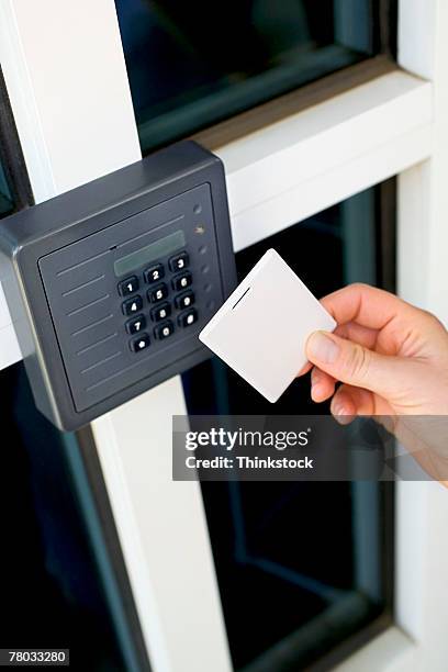 close-up of a woman holding a magnetic card up to the security keypad and reader at the entrance to a secured building - security pass stock pictures, royalty-free photos & images