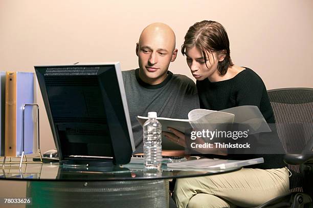 a man and woman sit at a computer working together on a project - parcialmente calvo - fotografias e filmes do acervo