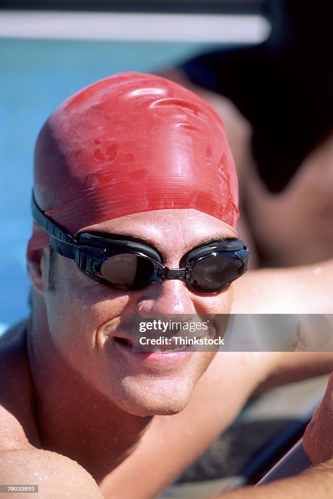 Portrait of competition swimmer wearing a swimcap and goggles, smiling at the viewer