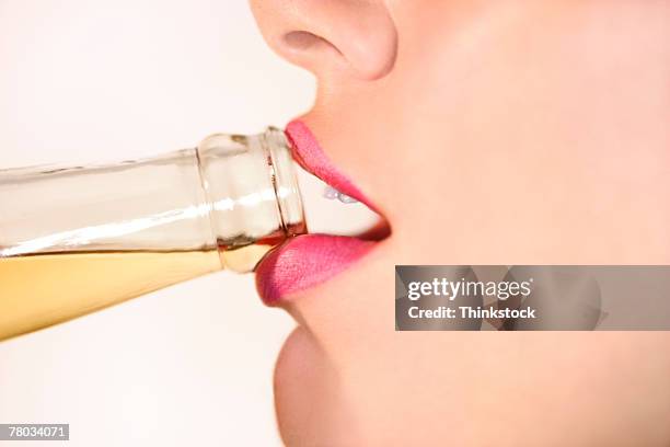 close-up profile view of a woman's lips drinking from a bottled beer - beer bottle mouth stock-fotos und bilder