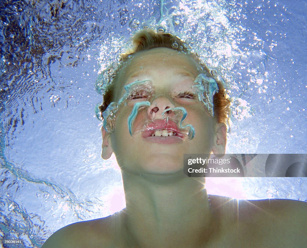 Underwater view of a boy blowing bubbles and making faces