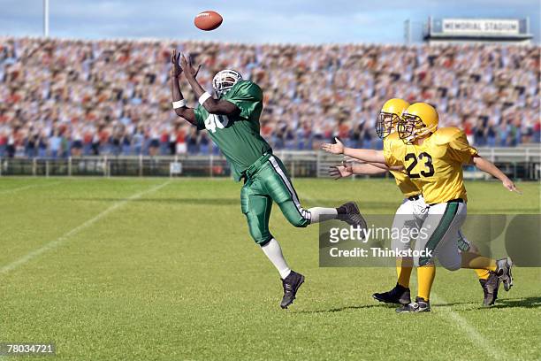 football player jumping for ball during game - high school football stock pictures, royalty-free photos & images