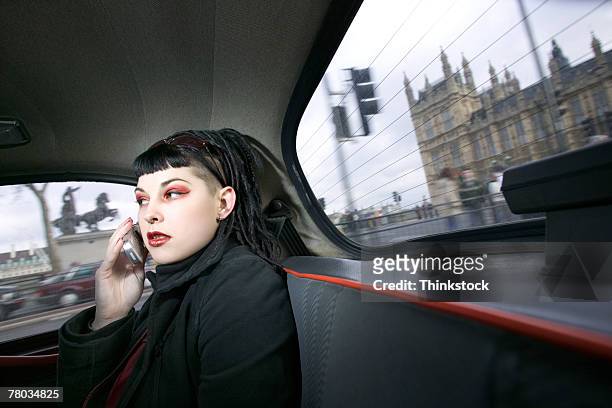 young goth woman using cell phone in cab while passing parliament building, london, england - goth photos et images de collection
