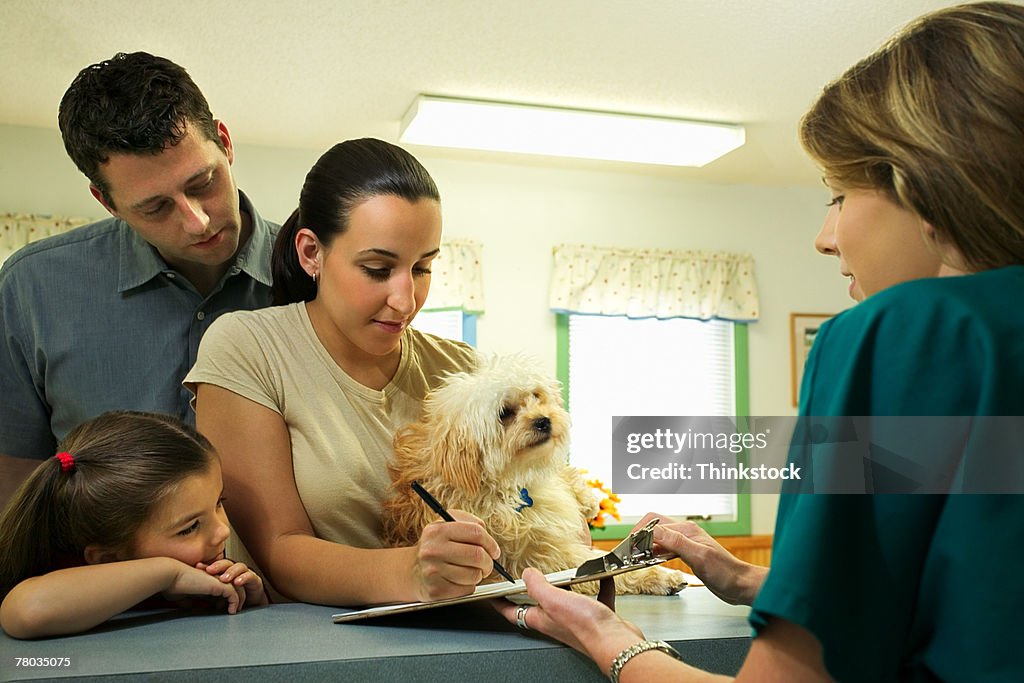 Family with dog filling out paperwork at vet clinic