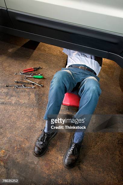 mechanic working while lying on creeper under car - trepadeira - fotografias e filmes do acervo