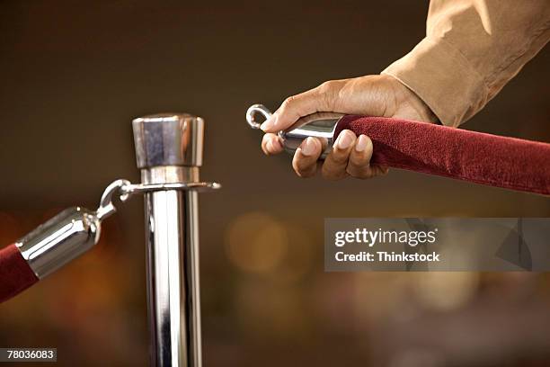 hand of man opening rope barrier - seilabsperrung stock-fotos und bilder