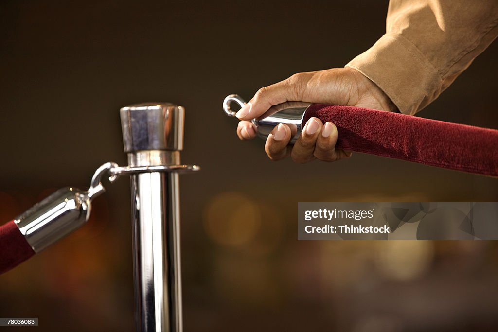 Hand of man opening rope barrier