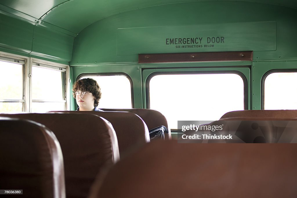 Teenage boy sitting alone in school bus