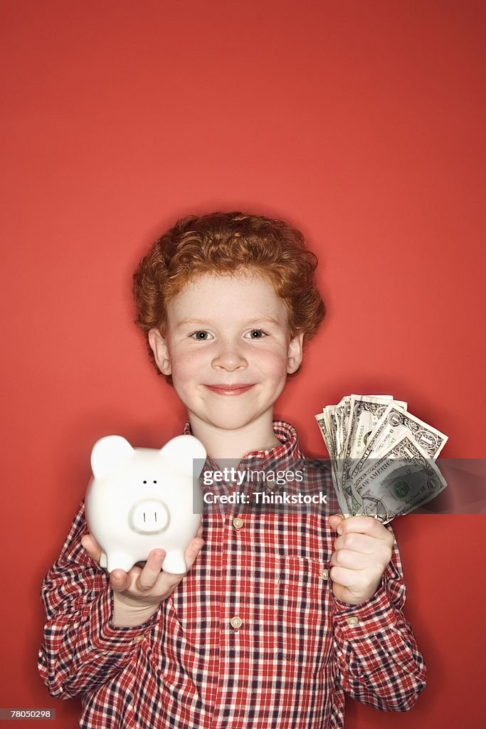 Boy with piggy bank and dollar bills