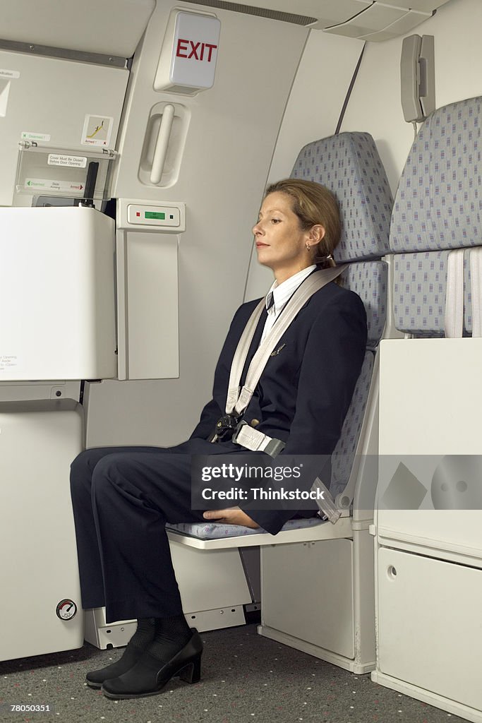 Flight attendant sitting in a jump seat