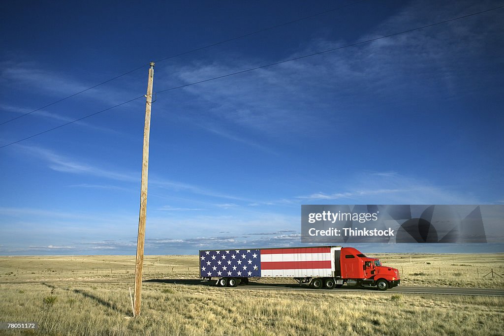 Semi truck with American flag on rural highway