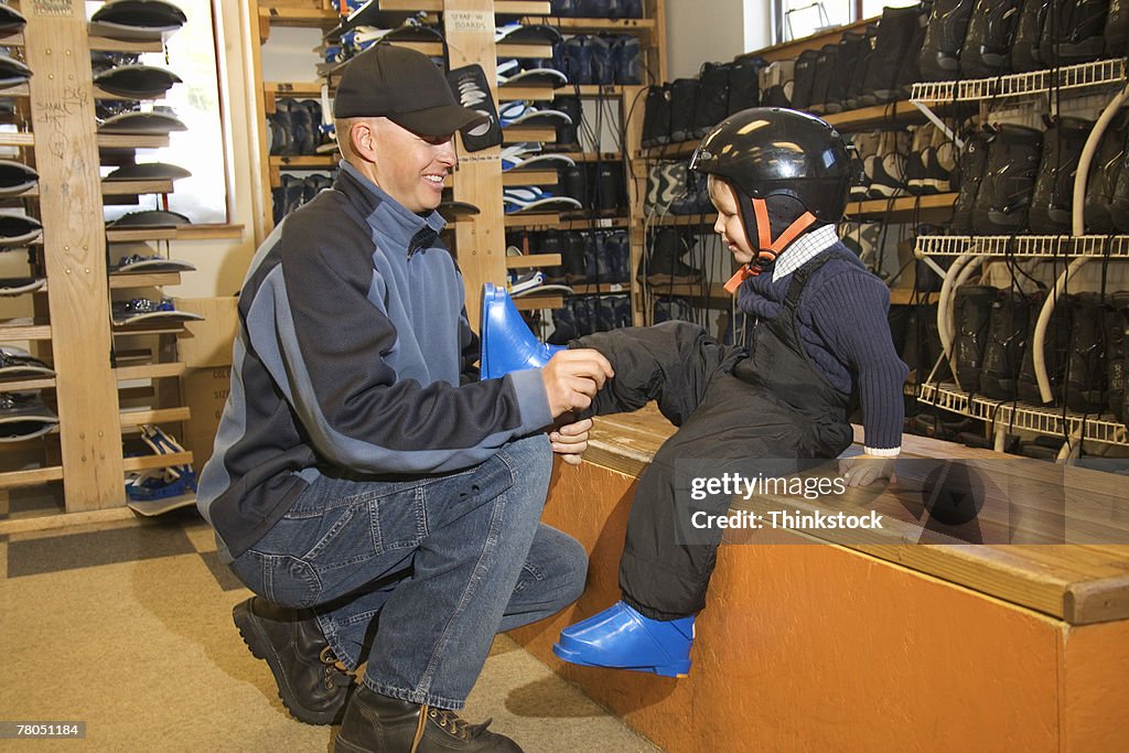 Man putting boots on boy in ski shop