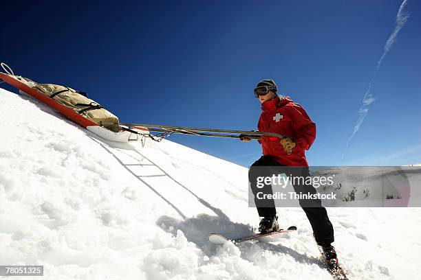 ski patrol pulling supplies on sled - ski patrol stock-fotos und bilder