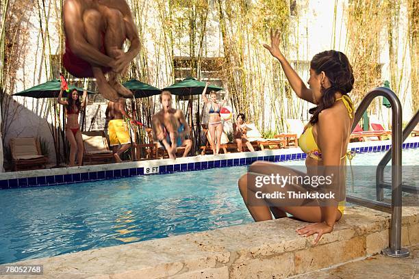 woman about to be splashed by man doing cannon ball - cannonball diving stock-fotos und bilder