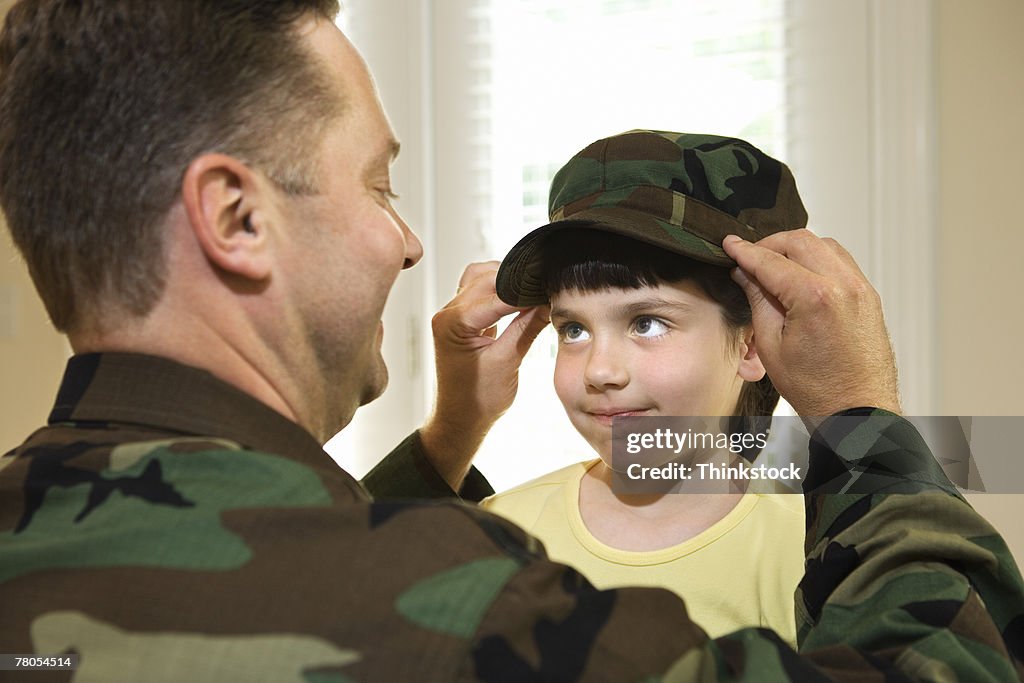 Soldier giving hat to daughter