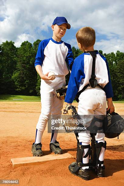 young baseball catcher and pitcher talking at the mound - baseball pitchers mound - fotografias e filmes do acervo