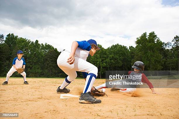 young runner sliding into base - baseball base stock-fotos und bilder
