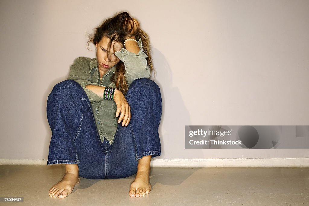 Unhappy woman sitting on floor