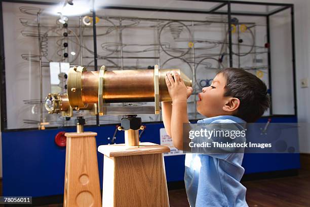 boy looking through telescope in museum - children museum stock pictures, royalty-free photos & images