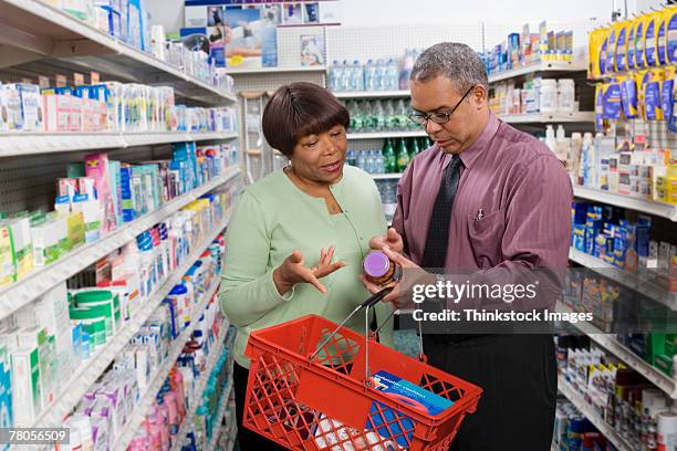 customers discussing medication in a pharmacy - t 55 stock-fotos und bilder