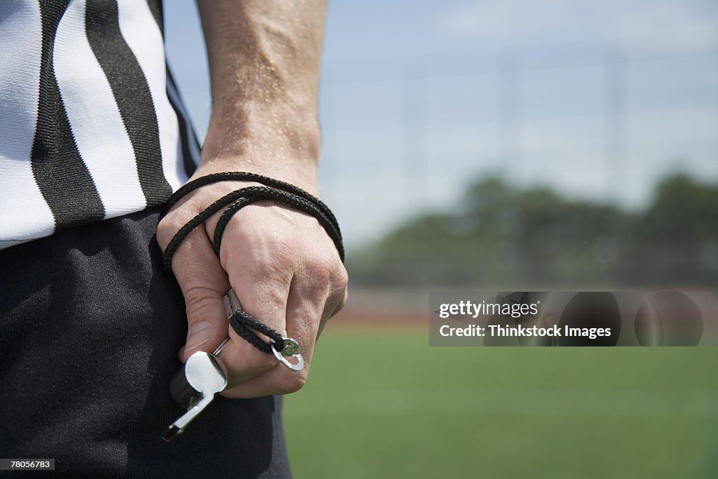 Referee's hand holding whistle