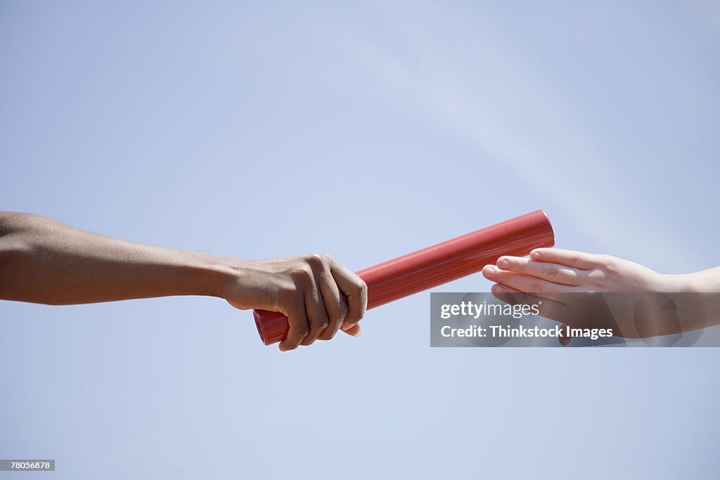 Relay runners' hands passing baton