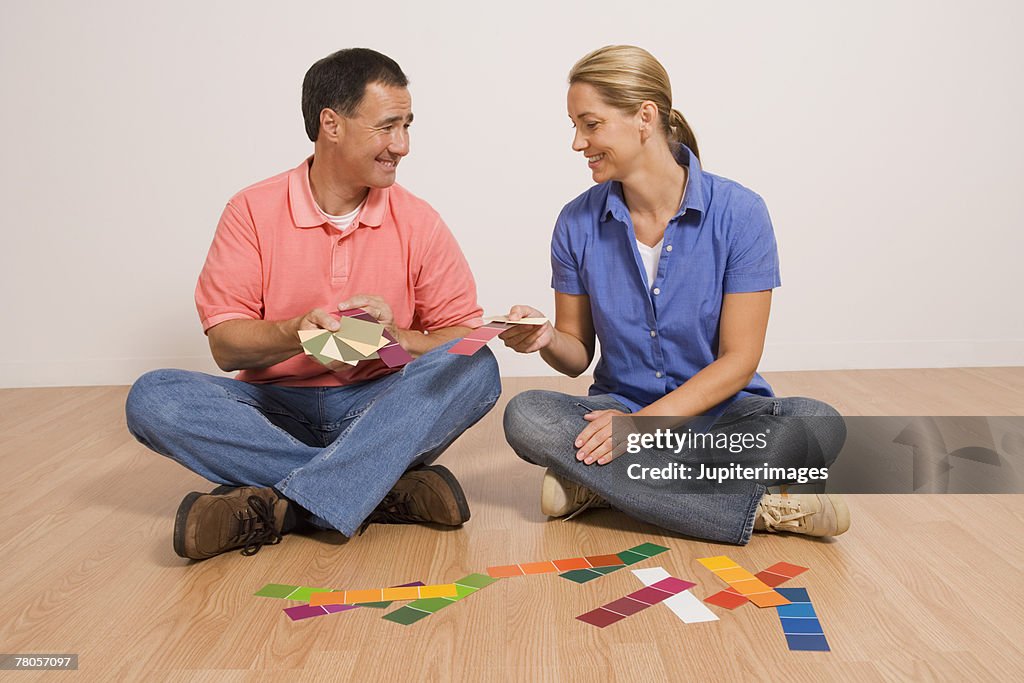 Man and woman sitting on floor with paint samples