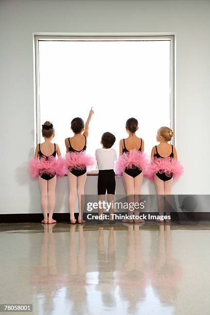 rear view of ballet students standing by window - ballet boy foto e immagini stock