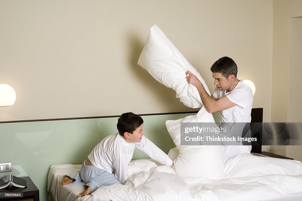 Father and son having a pillow fight in bed