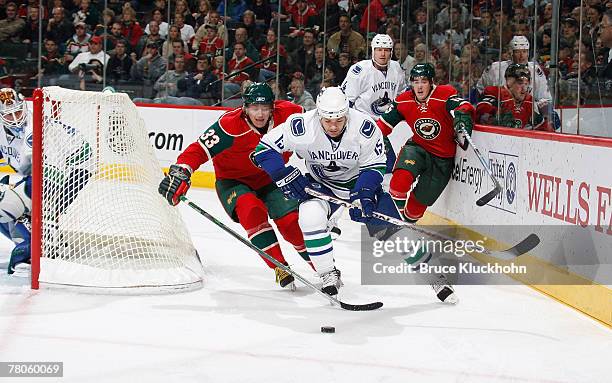 Byron Ritchie of the Vancouver Canucks and Petteri Nummelin of the Minnesota Wild try to gain control of the puck during the game at Xcel Energy...