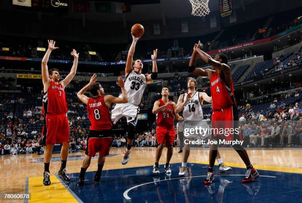 Mike Miller of the Memphis Grizzlies shoots between Jose Calderon and Chris Bosh of the Toronto Raptors on November 21, 2007 at the FedExForum in...