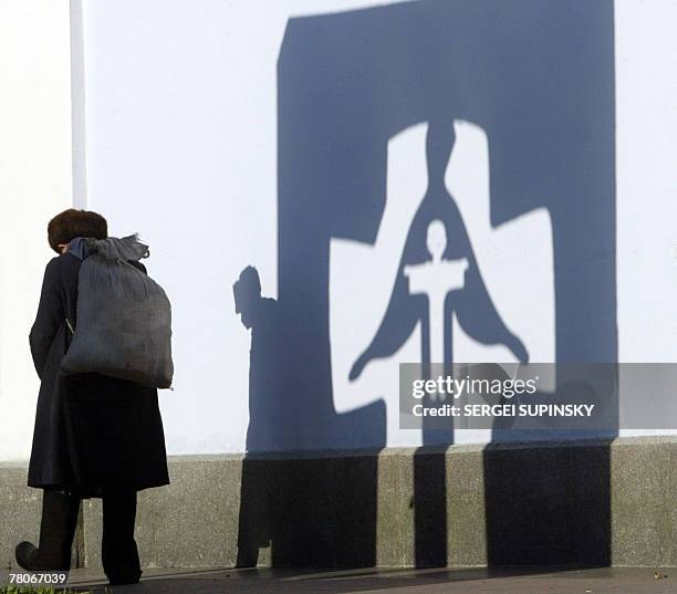 Picture dated November 2003 displays an elderly man passing a shadow of the Holodomor victims monument in Kiev. The monument erected for up to 10...