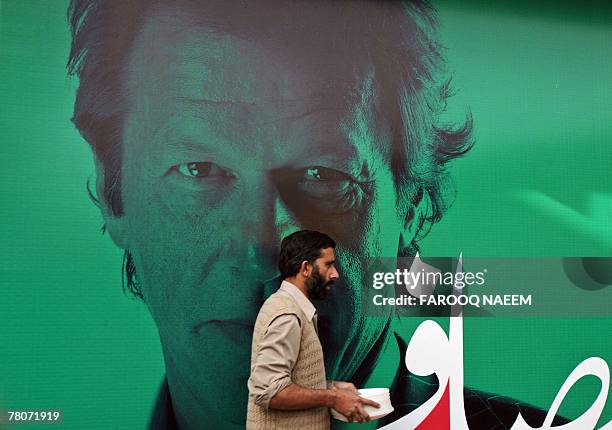 Pakistani worker walks in front of a poster of cricketer turned politician Imran Khan at his party secretariat in Islamabad, 22 November 2007. Khan,...