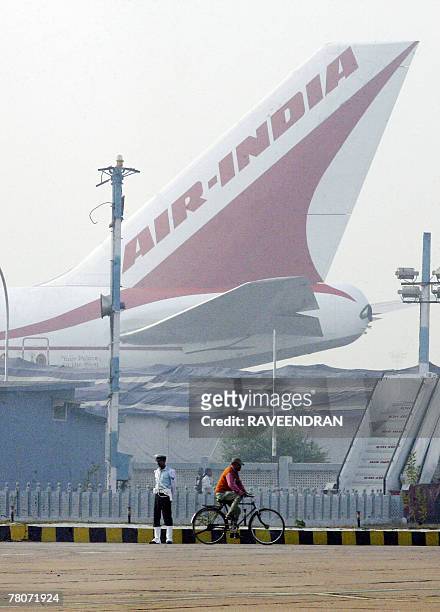 An Indian man rides his cycle past the tail of an Air India plane at the airport in New Delhi, 22 November 2007. Six Air India flights out of Delhi's...