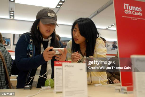 Diane Song and Jennifer Song of Hockessin, Delaware look at an iPhone in the Apple store at the King of Prussia Mall November 23, 2007 in King of...