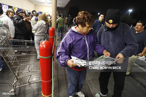 Early morning shoppers check a circular for advertised special prices as they await the 5:00am opening of a Wal-Mart store, in Panorama City,...