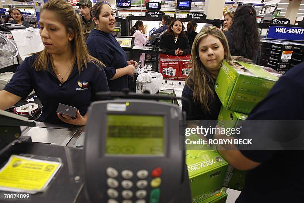Sales associates bring Xbox game consoles to the counter for early morning shoppers at a Wal-Mart store in Panorama City, California, 23 November...