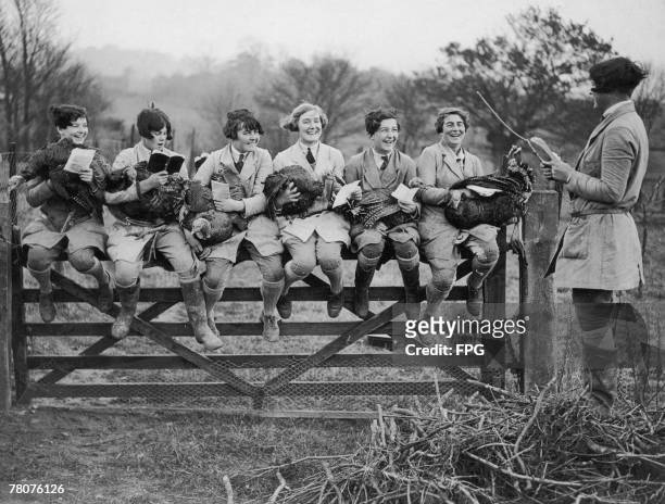Group of farm workers holding turkeys as they practice singing Christmas carols on a poultry farm in Welwyn, Hertfordshire, 29th November 1929.