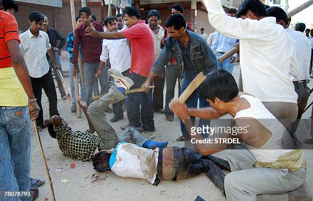 Indian residents beat protesters as they lie on a road of Guwahati, 24 November 2007, after activists of All Adivasi Student?s Association of Assam...