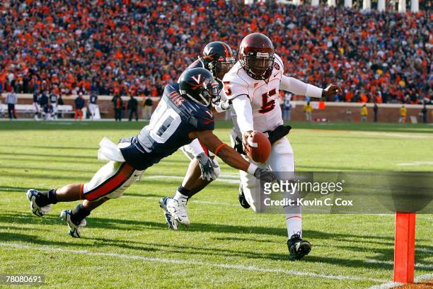 Quarterback Tyrod Taylor of the Virginia Tech Hokies scores a touchdown against defenders Nate Lyles and Jermaine Dias of the Virginia Cavaliers...
