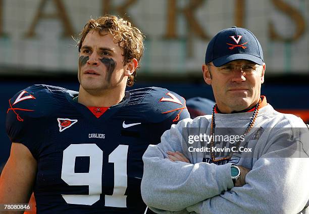 Defensive end Chris Long of the Virginia Cavaliers stands with his father and Pro Football Hall of Famer Howie Long before Chris' jersey retirement...