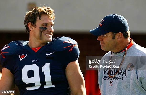 Defensive end Chris Long of the Virginia Cavaliers stands with his father and Pro Football Hall of Famer Howie Long before Chris' jersey retirement...