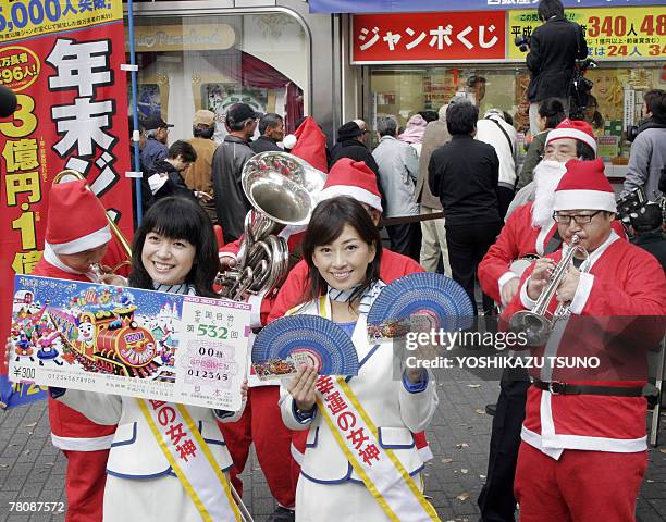 Campaign girls Arata Matsumoto and Risa Sugimoto display smple lottery tickets for the 300 million yen Year-End Jumbo Lottery before a Tokyo ticket...