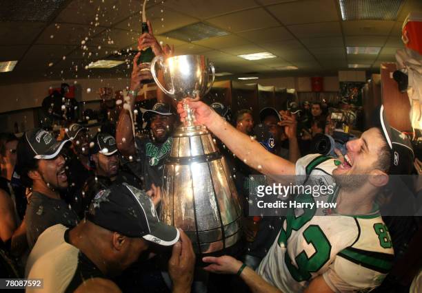 Andy Fantuz of the Saskatchewan Rough Riders hoist the trophy amongst champagne in celebration of a victory over the Winnipeg Blue Bombers during the...