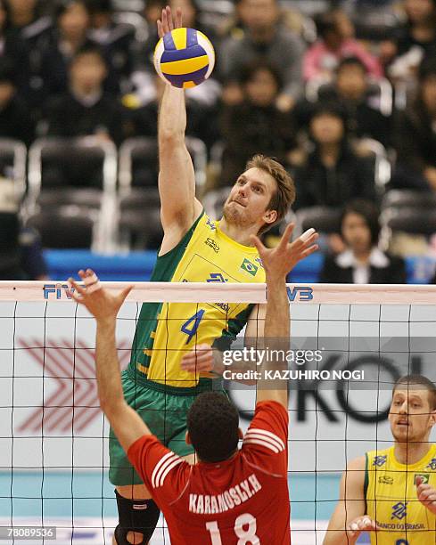 Brazilian attacker Andre Heller spikes the ball over Tunisian blocker Hosni Karamosly during their match at the FIVB Men's World Cup volleyball...