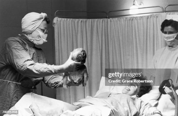 Nurse handing a newly born baby to its mother, 1956. Original Publication: Picture Post - 9111 - Analgesia - unpub.